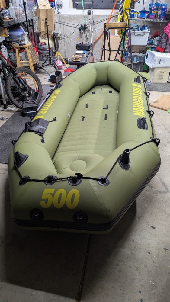 A navigator 2 inflatable raft. It is green with a 500 on the front of it. It is sitting in a messy garage.