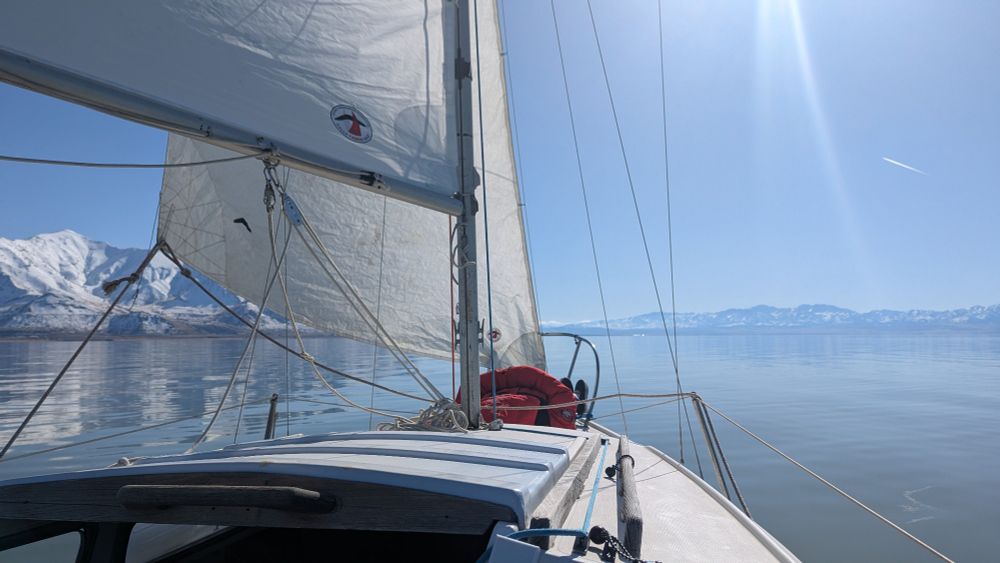 A boy lays under the sails on a cold winter day aboard a sailboat.

