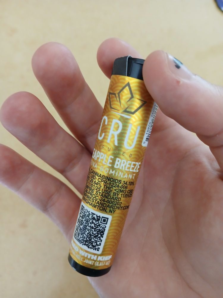 Gold labeled black preroll tube held in my hand
