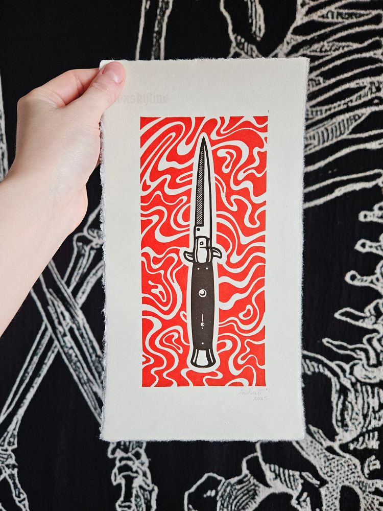 Linocut print of a black switchblade surrounded by red swirls