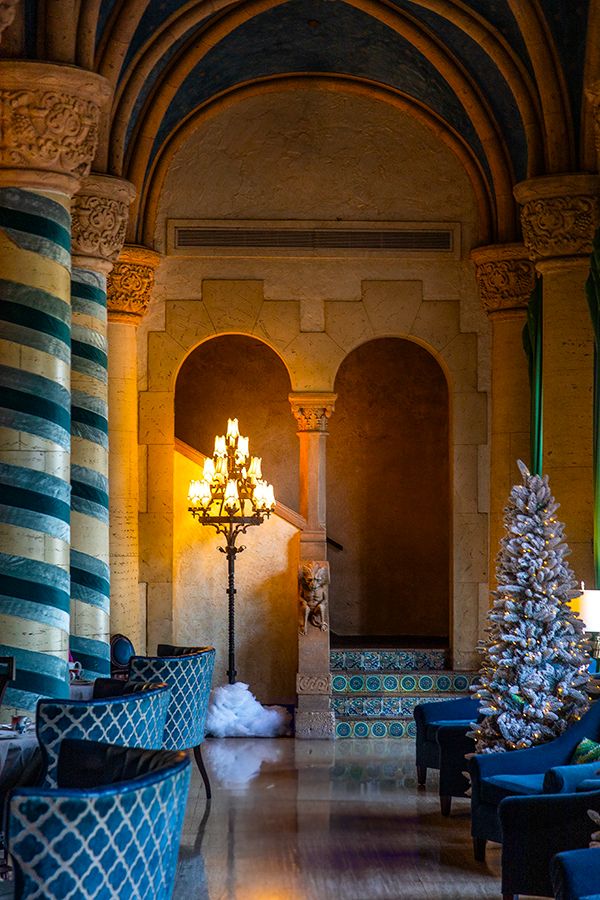 The Biltmore Hotel lobby in Coral Gables, Florida, adorned with holiday decor, a grand candelabra, christmas tree, and a staircase.