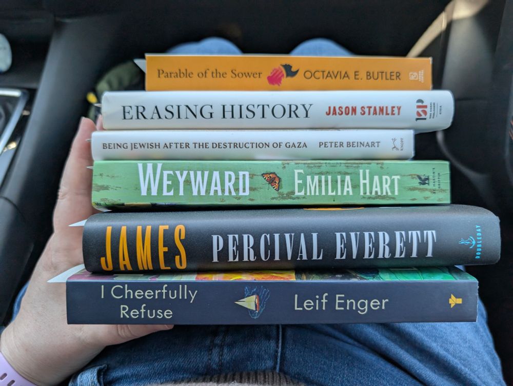 Stack of new books, featuring Parable of the Sower, Erasing History, Being Jewish After the Destruction of Gaza, Weyward, James, and I Cheerfully Refuse