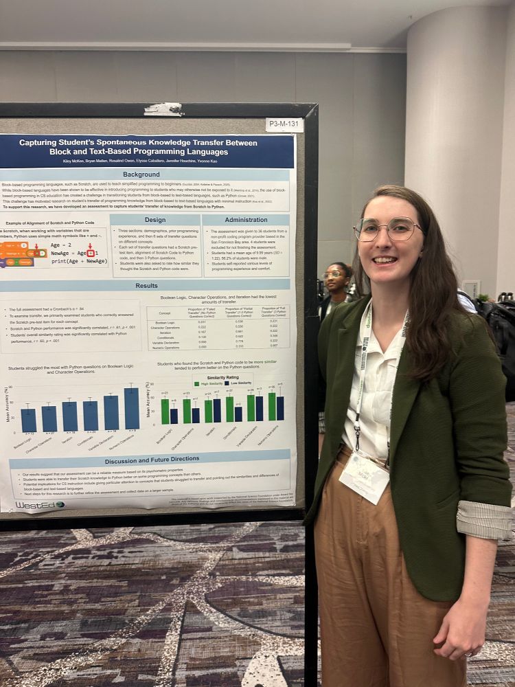Kiley stands in green blazer and brown pants next to academic poster about a transfer assessment for student transiting from Scratch to Python. 