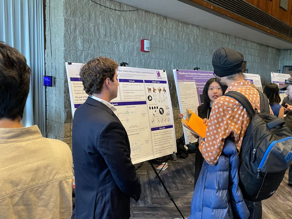 Two students presenting their research  poster for an individual