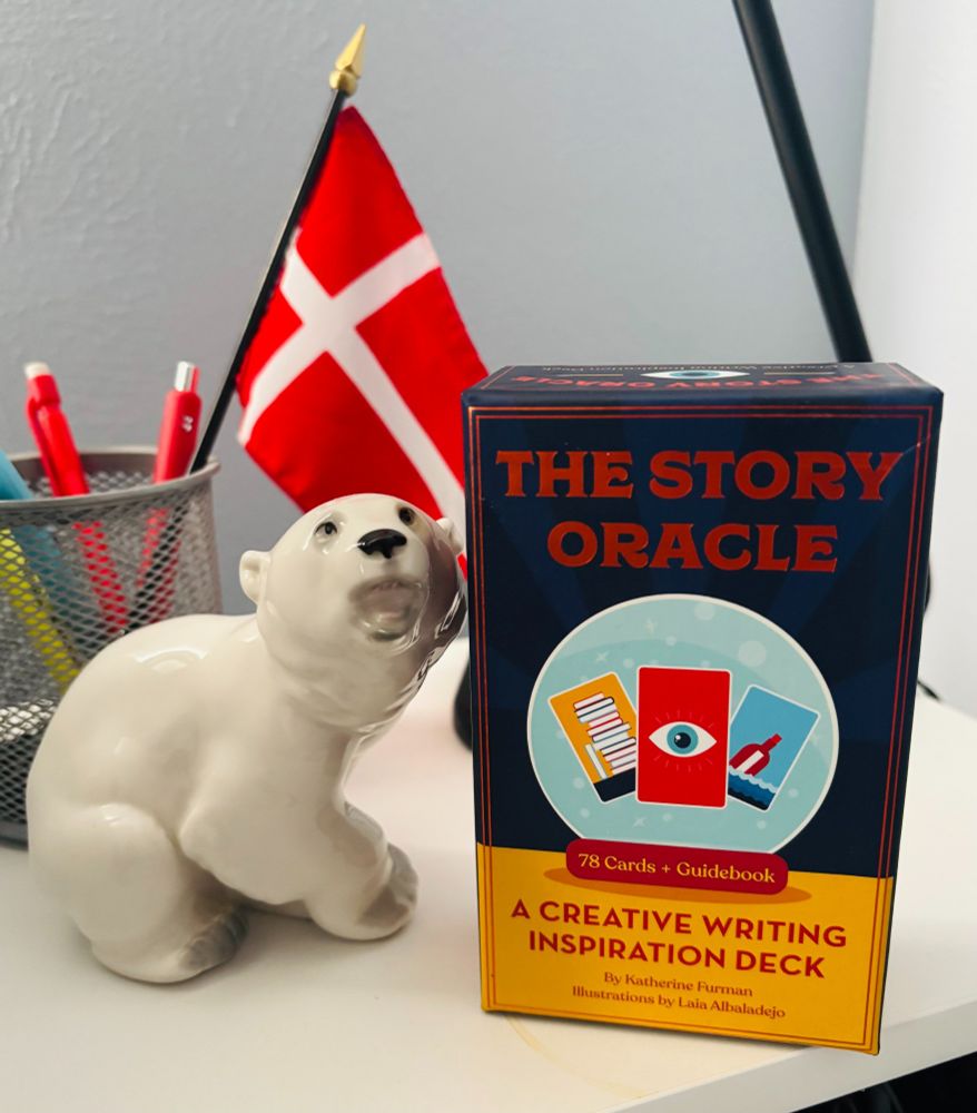 A polar bear figure, jar of pens with the Danish flag, and The Story Oracle Cards deck on a desk
