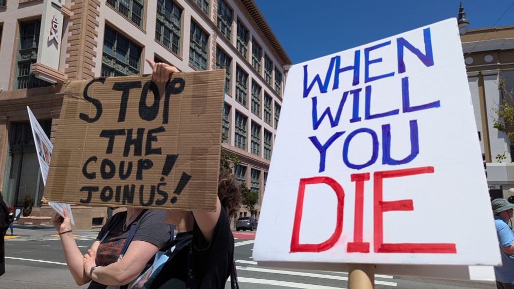 Two signs at a Tesla protest. One is "Stop the coup! Join us!", the other "When Will You Die", a song from the album Join Us.
