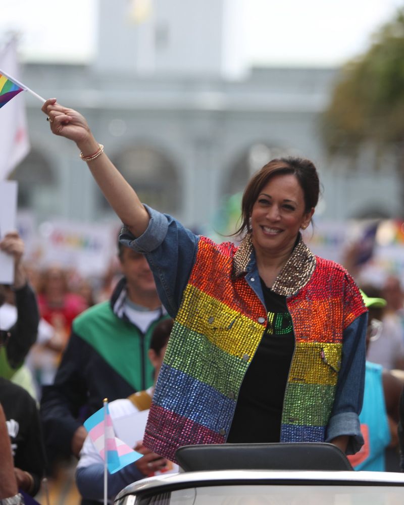 Vice President Harris waves a Pride flag and wears a rainbow sequin jacket while participating in San Francisco Pride in June 2019.