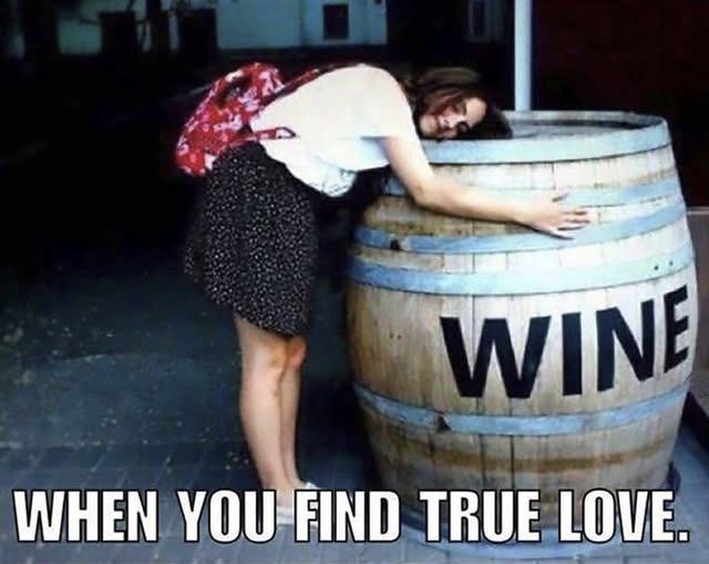 A woman hugging a large wooden keg of wine.