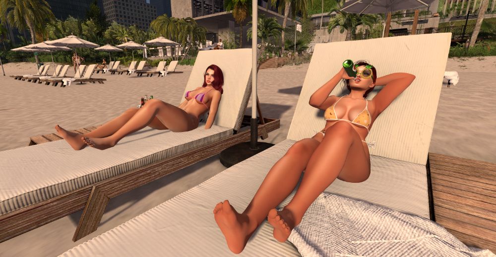 Two women laying on sunbeds at a resort beach. 