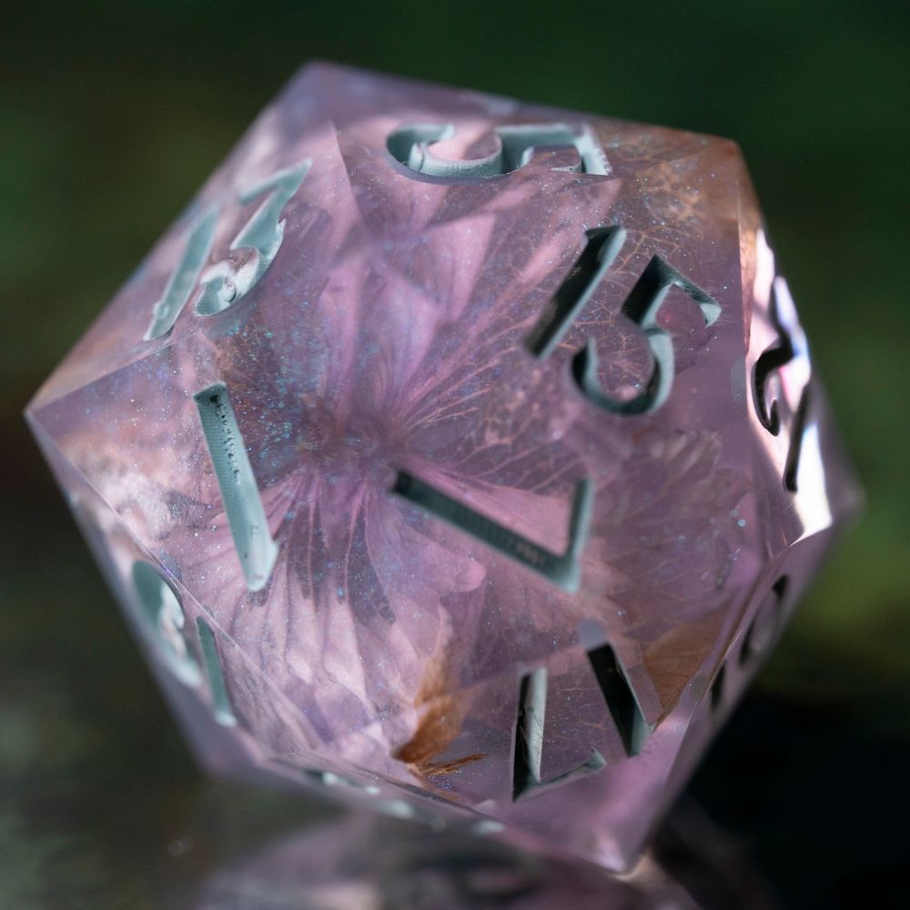 A 20-sided die, made of blue-purple iridescent resin with a hydrangea flower inclusion