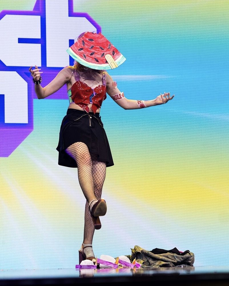 Photo de Clek avec un masque pastèque sur la scène du dragshow de la Twitchcon 