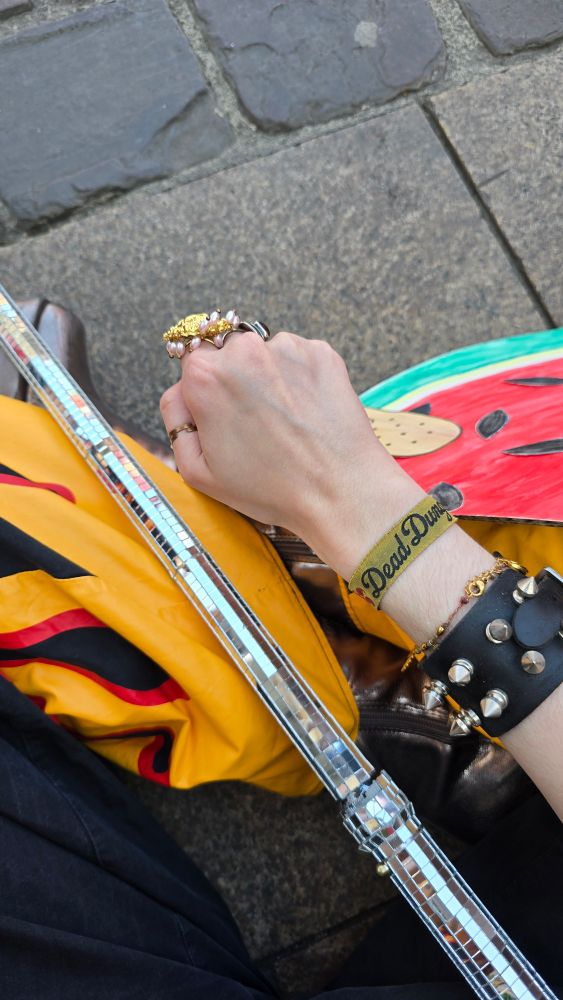 Mon poing tendu on voit derrière un bout de mon pantalon flammes, ma canne et ma pancarte pastèque car je suis assise