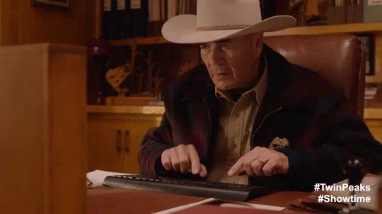 a man in a cowboy hat typing on a keyboard