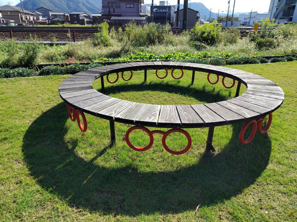 赤い眼鏡モチーフのついたベンチ。ハピラインふくいの線路沿いにある。