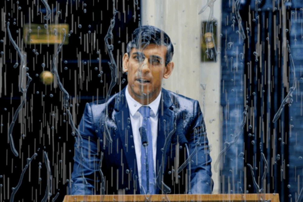 a man in a suit and tie stands at a podium in front of a window that is covered in water