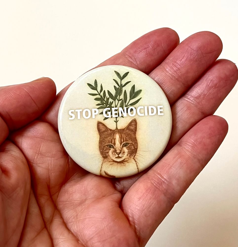 手のひらに乗せたアイーダ缶バッジ
STOP GENOCIDE の文字