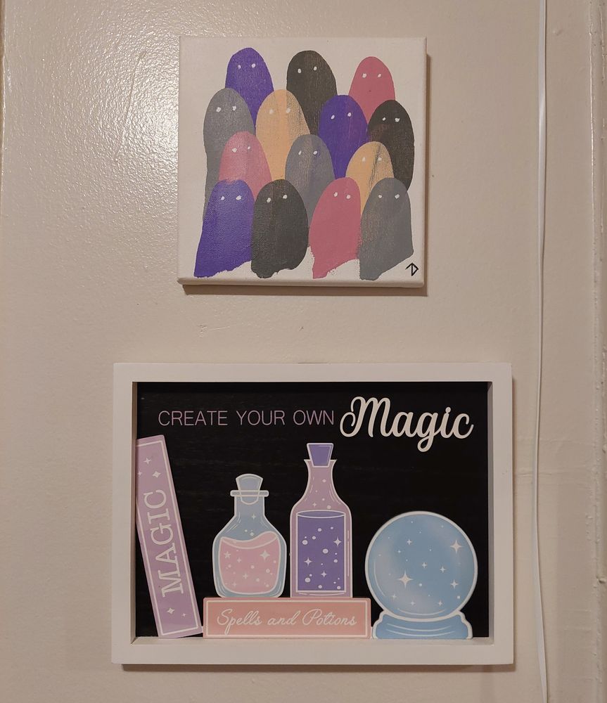 A Michaels craft store wall sign in pastel colors that says Create Your Own Magic above images of spell books ans potion bottles. 