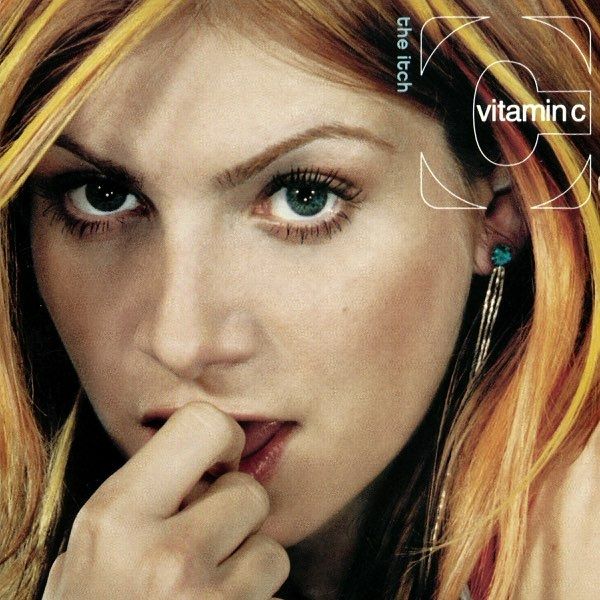 Cover image of Vitamin C, The Itch. A close-up of the singer with orange hair biting her finger and staring into the camera.