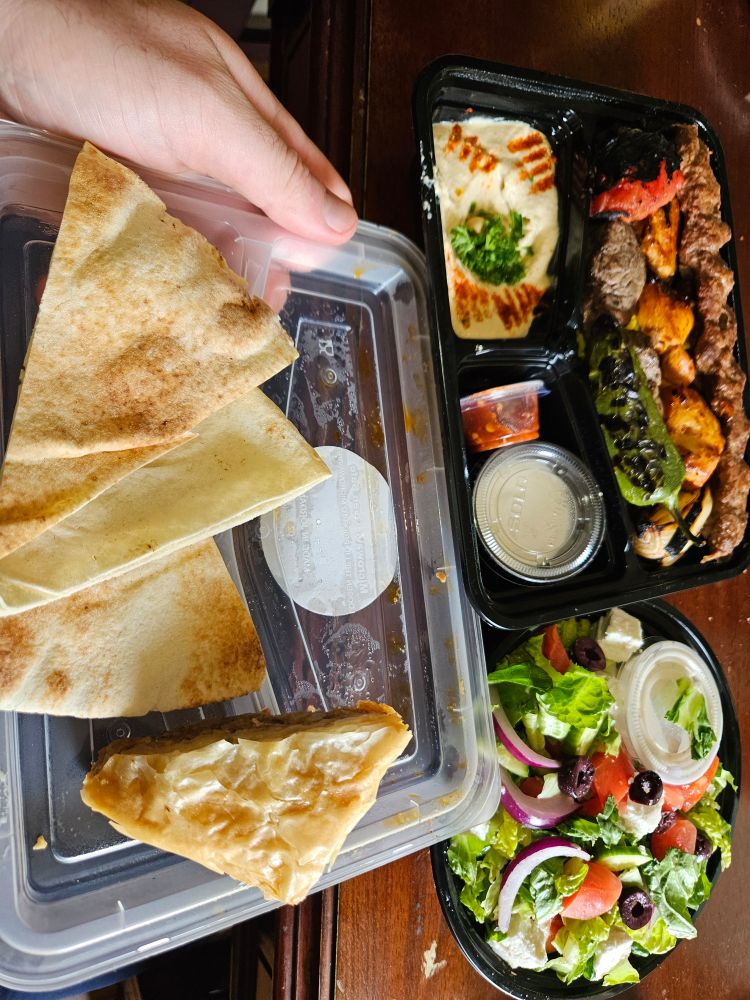 Pita, hummus, kebab with rice, sauces, greek salad, and baklava