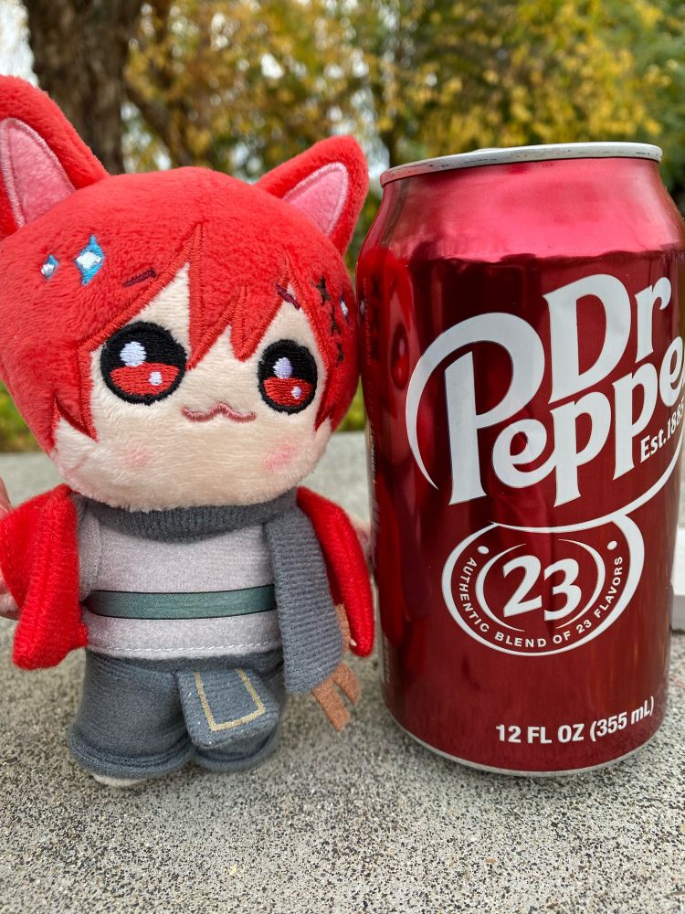 Graha plushie standing proudly next to dr pepper can