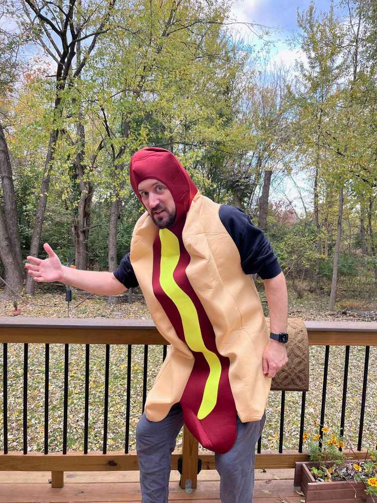 Me in a very cheap hotdog costume on my deck, standing like the “we’re all looking for the guy who did this” meme.