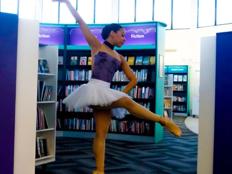 A lady ballerina dancing in a library