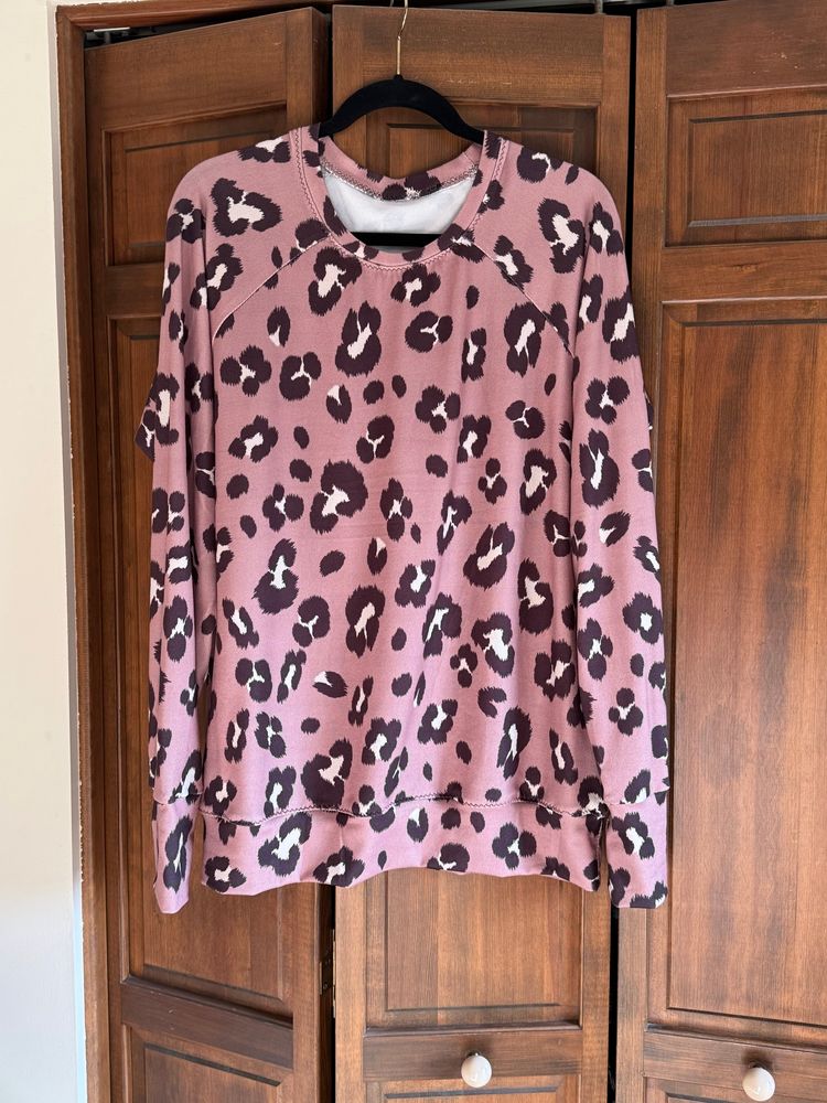 Mauve, big leopard print sweatshirt on a hanger in front of a closet. 