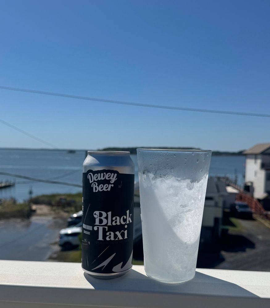 Black Taxi stout next to a chilled glass on the railing over looking the water