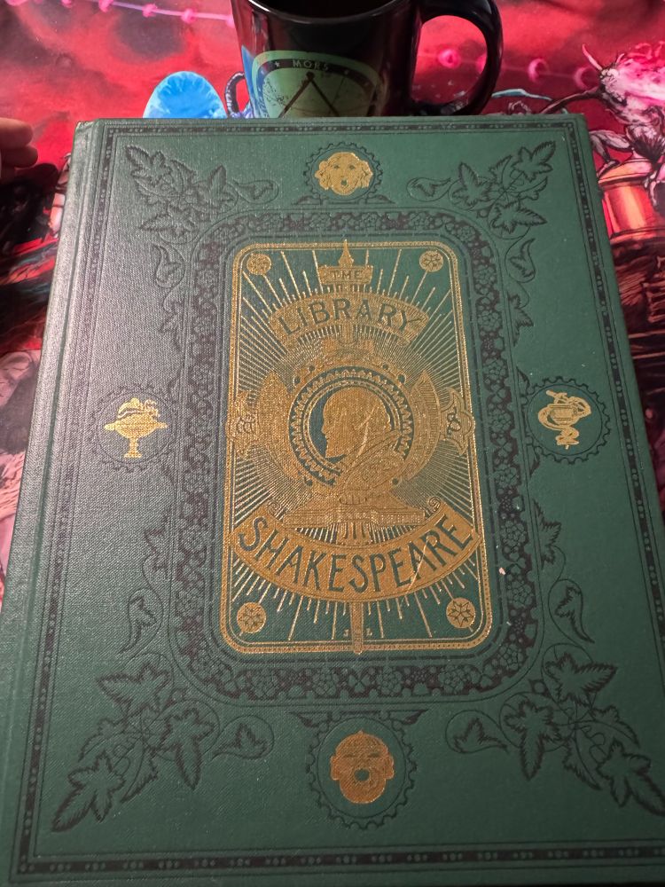 Library Shakespeare green cover on a Haunted West mousepad below a Delta Green coffee mug. 