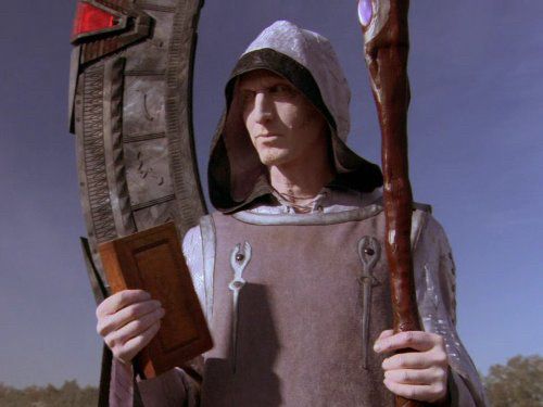 Picture shows an Ori Prior standing in front of a stargate. He is clad in grey with a foul look upon him, a staff in one and a bible in the other. This is an allegory for religious evangelicals being virulent, evil nutters.