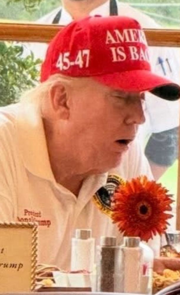 Donald Trump sitting at a table with his eyes closed and mouth slightly open