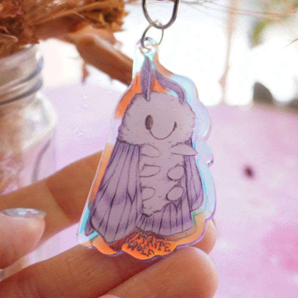 acrylic keychain of a sleepy moth with a holographic gleam