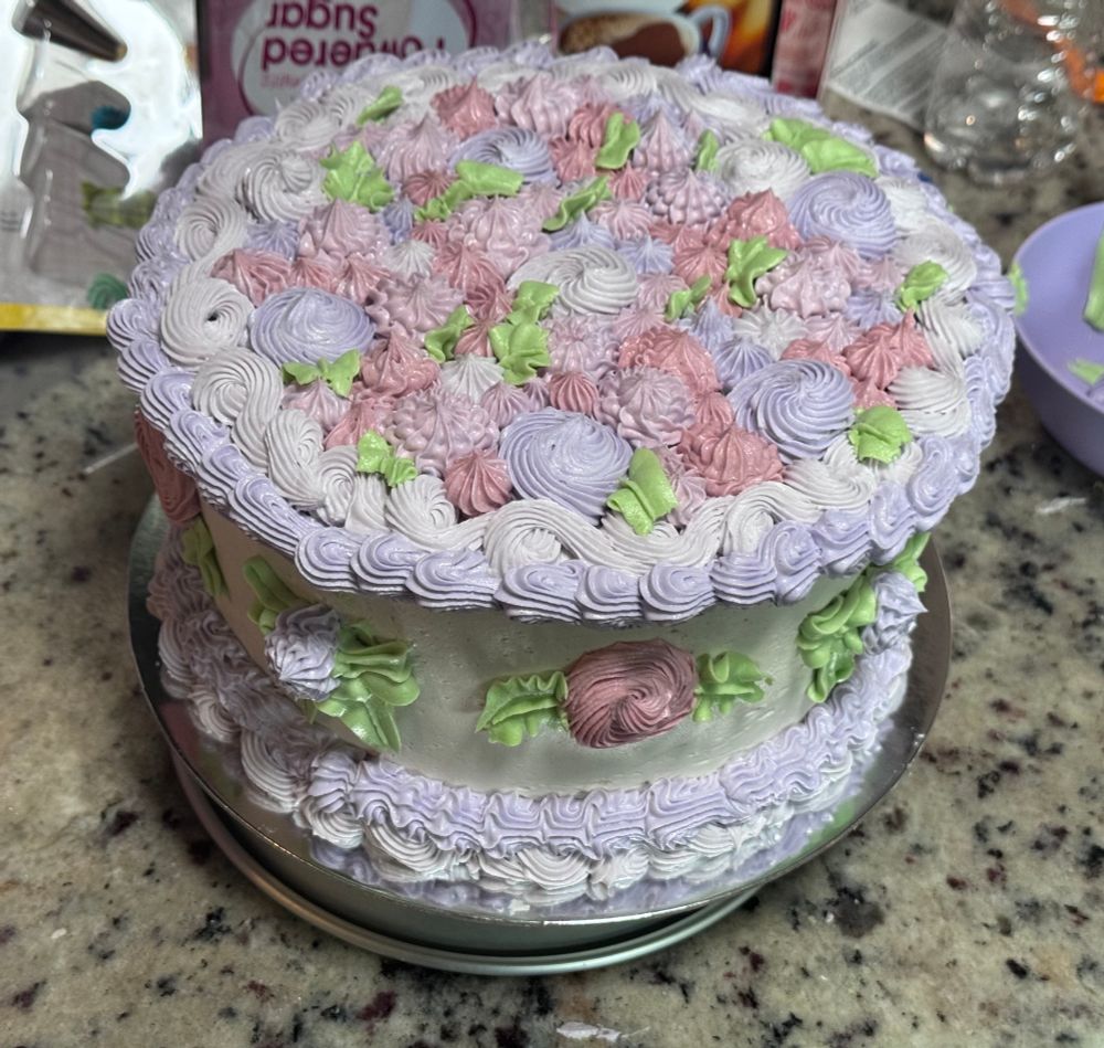 Homemade cake with vintage style piping designs in pastel purple, pink and green. 