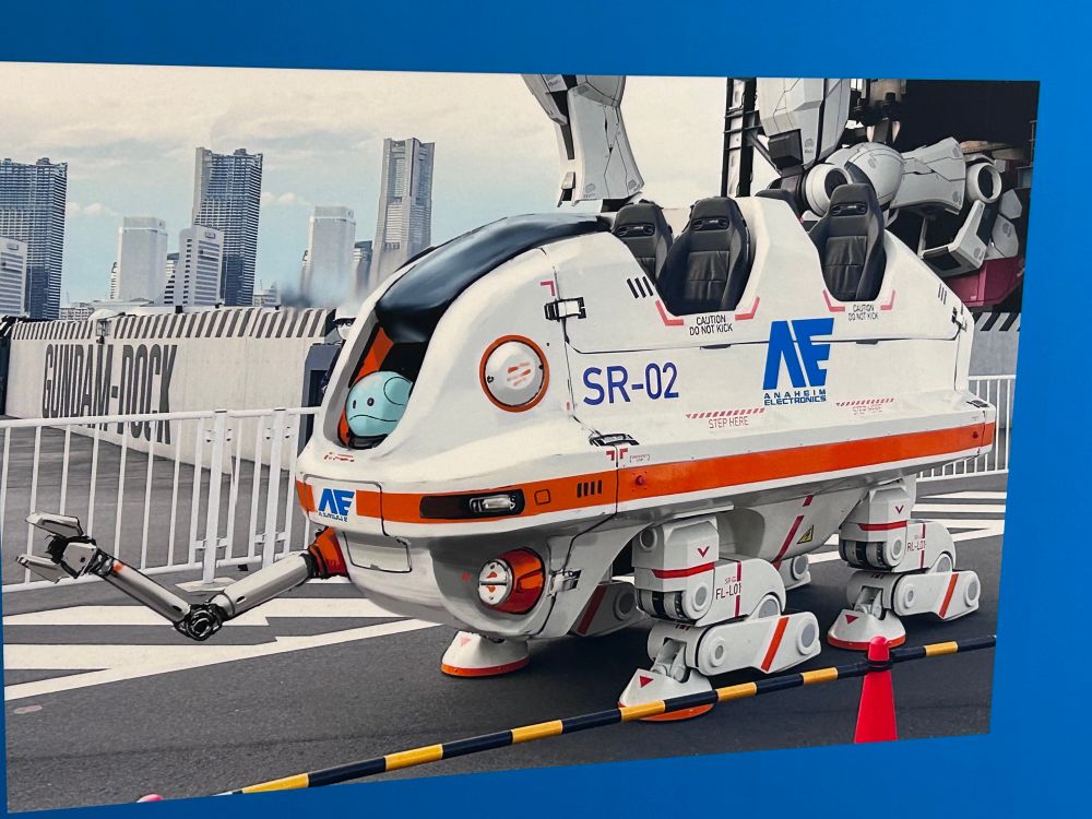 横浜ガンダムの足元で大きな四つ足歩行のメカに乗っているハロの模型の写真が紹介されている。ハロは絵で描き込まれていて、おそらく写真も合成。