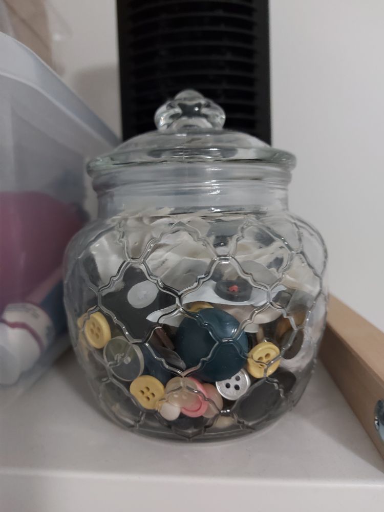 A jar of buttons on a shelf