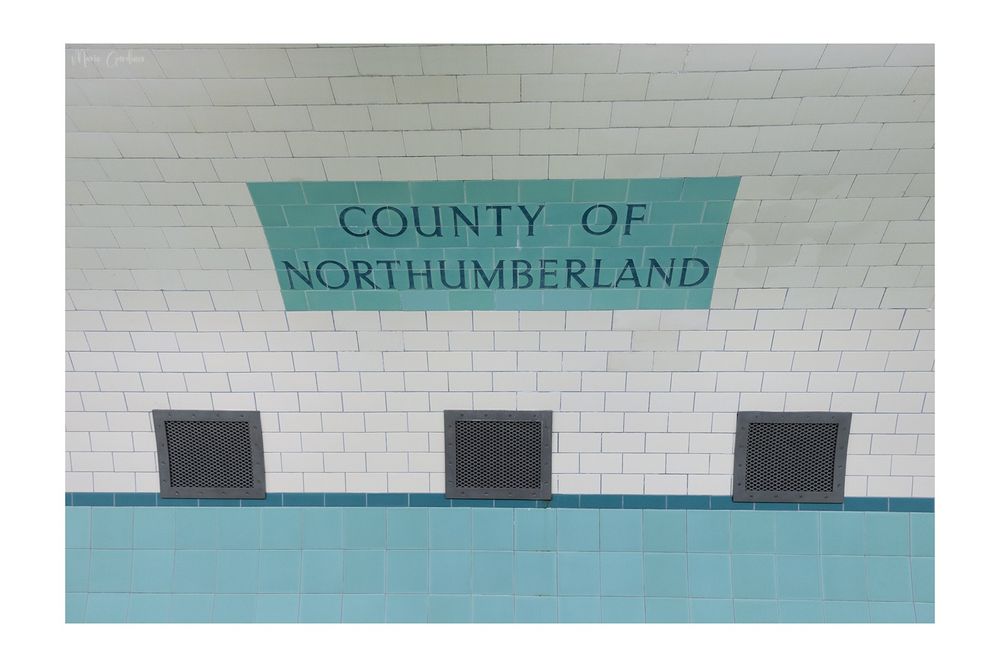 tiling that says 'county of northumberland' with 3 vents below and a strip of turquoise tiles