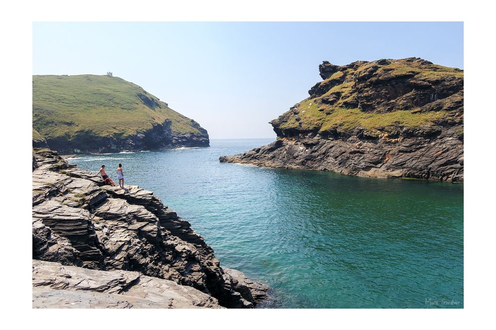 a sea inlet in a zigzag with cliffs around it and a couple lounging on one of the cliffs