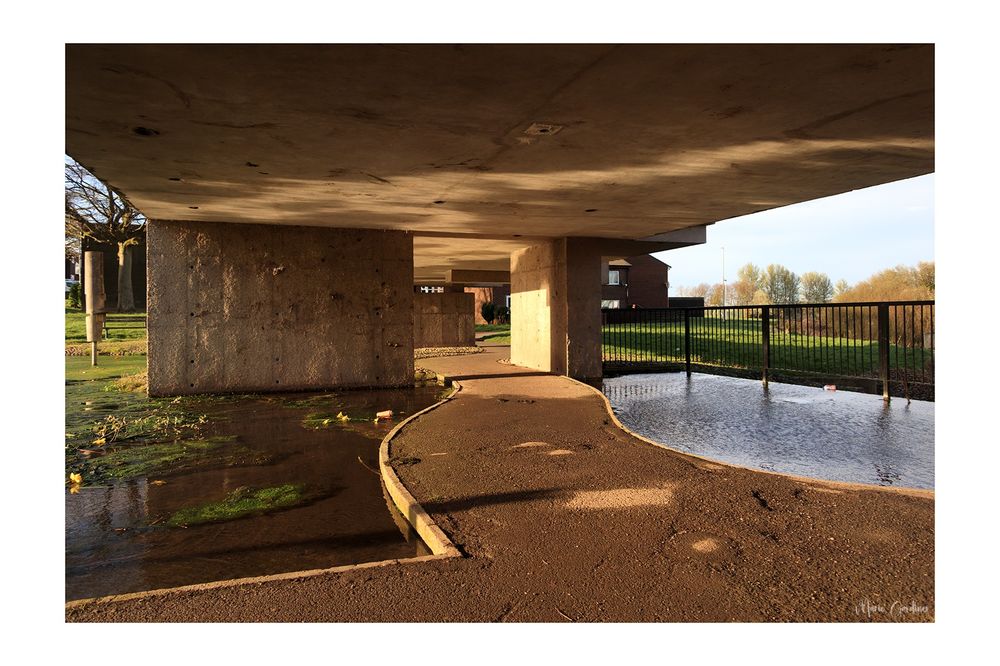 a path leading under the pavilion, with water to both sides