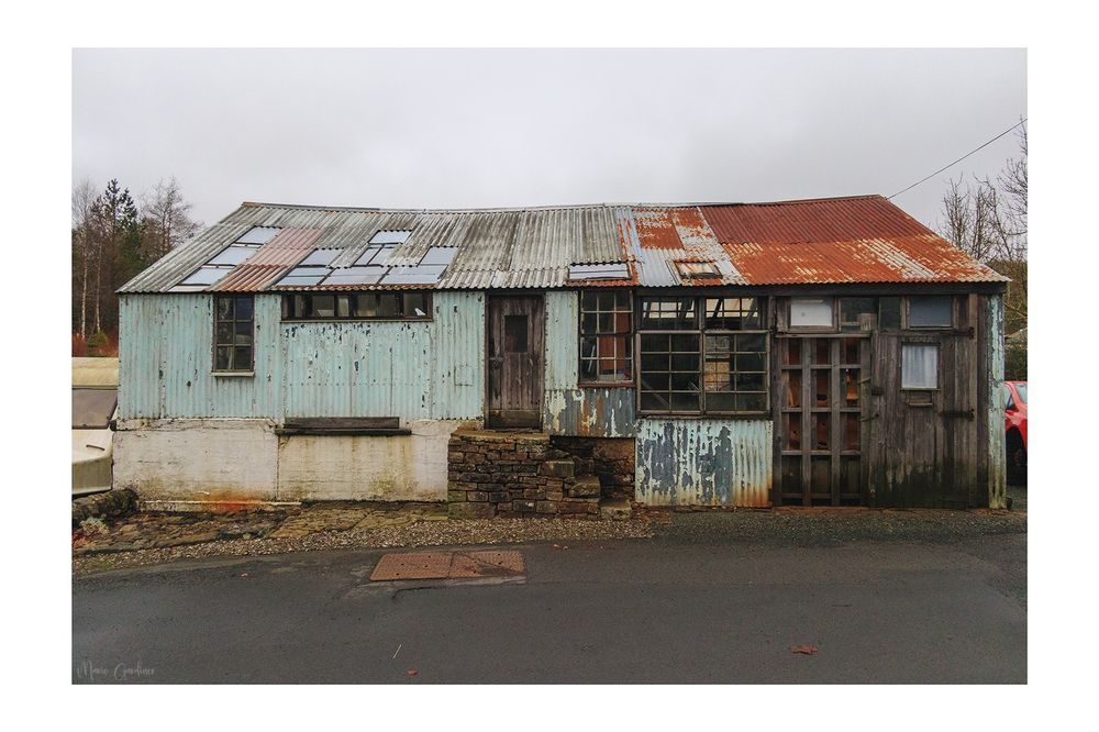 a wide, mostly corrugated iron hut, with various different colours, doors, and windows