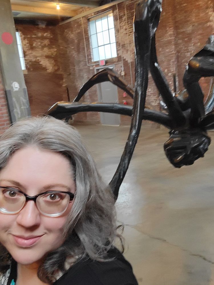 A bespectacled curator and a Louise Bourgeois giant bronze spider sculpture at Dia Beacon