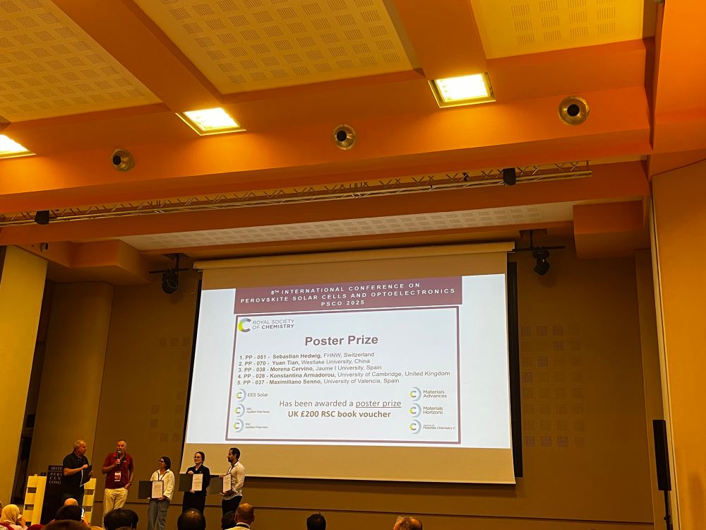 3 researchers with certificates on stage with the organisers and chairs of the conference 