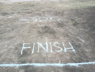 A white line on grass and dirt with "Finish" written in white above it. And above that, "#300". Celebrating 300 ParkRuns at the Himmel course.