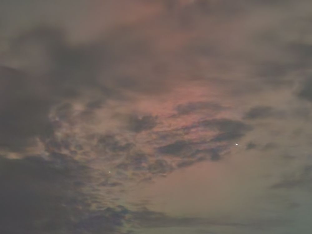 The Northern Lights and a few stars visible through clouds.