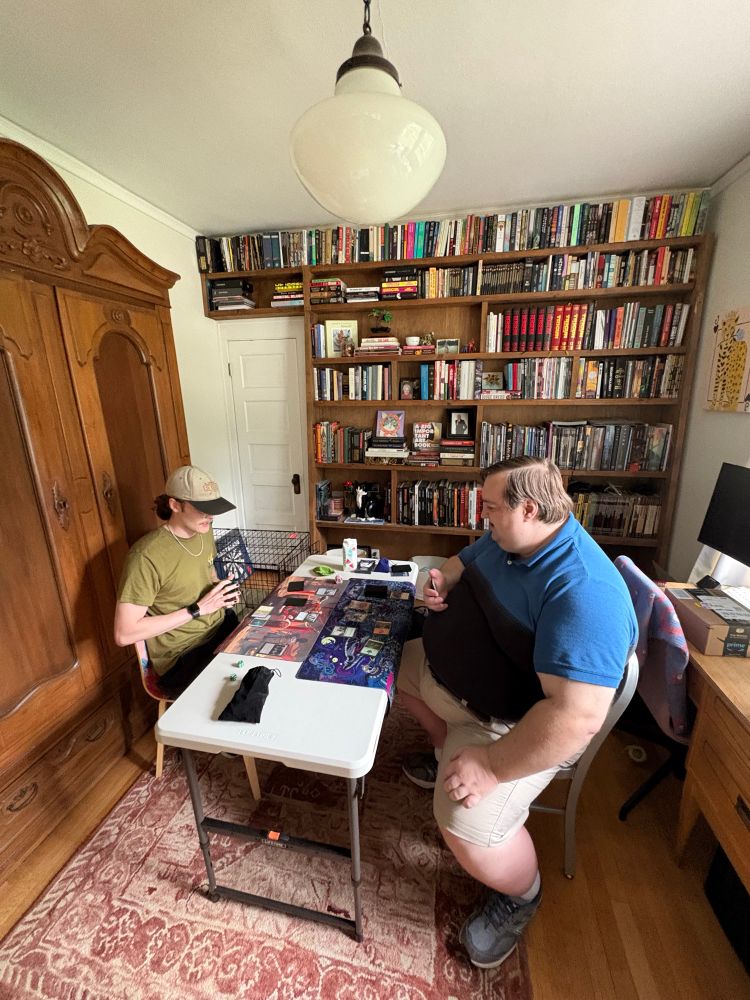 Two people sitting at a card table playing magic. 