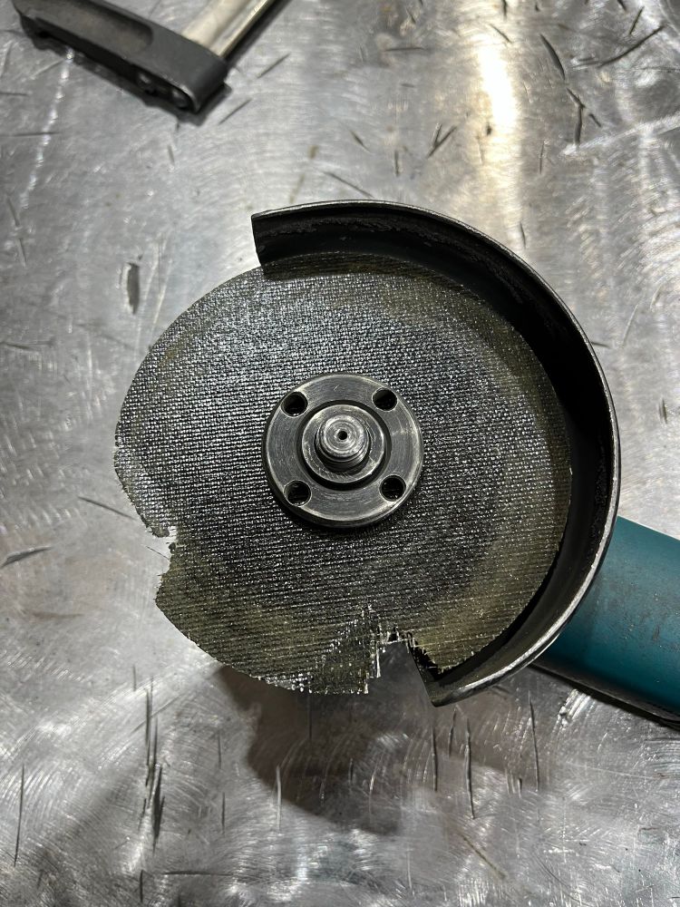 An angle grinder with two large chunks torn out of the cutting disc 