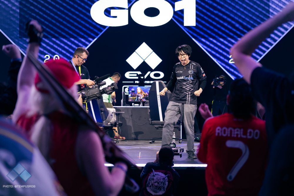 Photo of GO1 reacting to winning Fatal Fury: City of the Wolves at Evo. He's facing the crowd as they cheer for him.