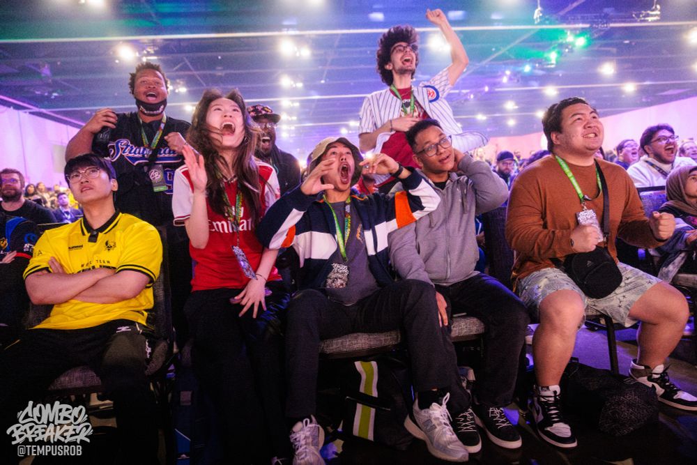 Photo of spectators getting excited while watching a match. Several spectators are also not cheering.