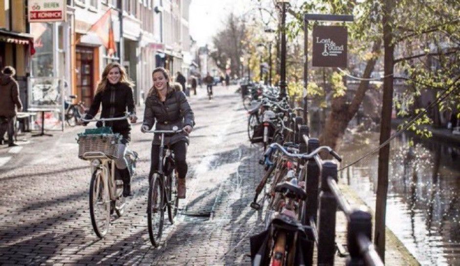 People riding bikes along a canal in Utrecht, Netherlands.
