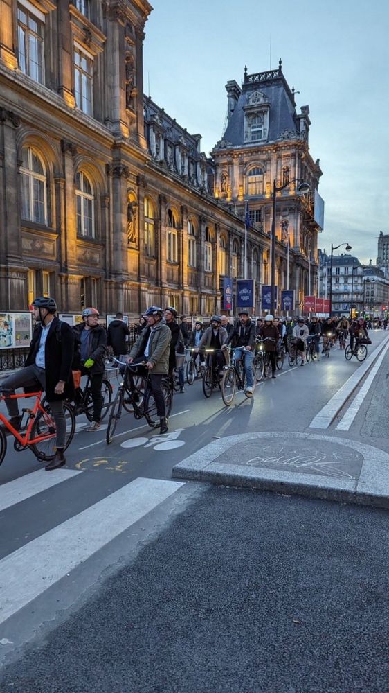 People lined up on bikes in a Paris protected bike lane waiting for the light to change.