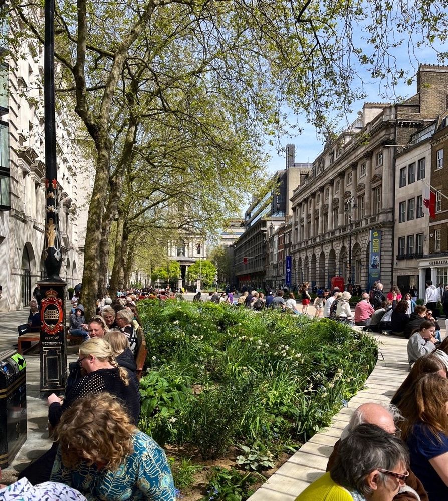 New greenspace and low-wall seating around it filled with people